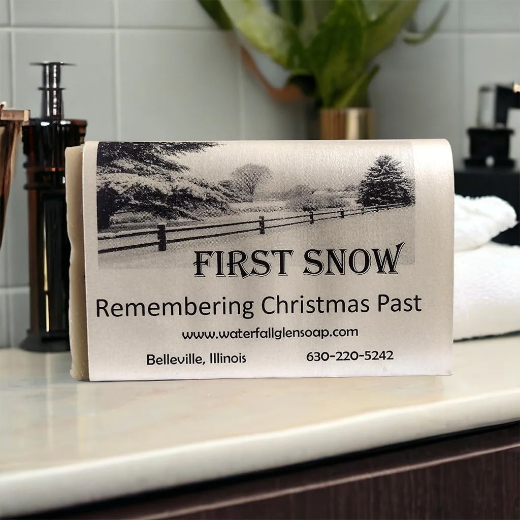 first snow soap with a white wrapper with a graphic of snow and trees on a plain behind a wooden fence