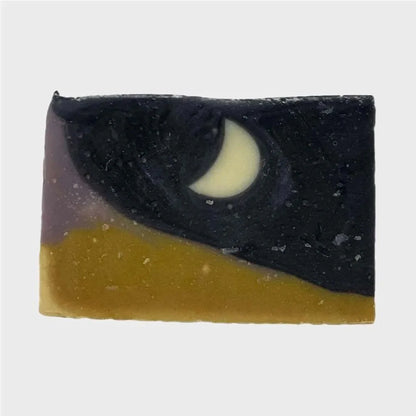 moonlight over morocco with an upper black and purple color, with a moon shape inside the bar of soap. While a yellow and purple color on the bottom of the bar soap