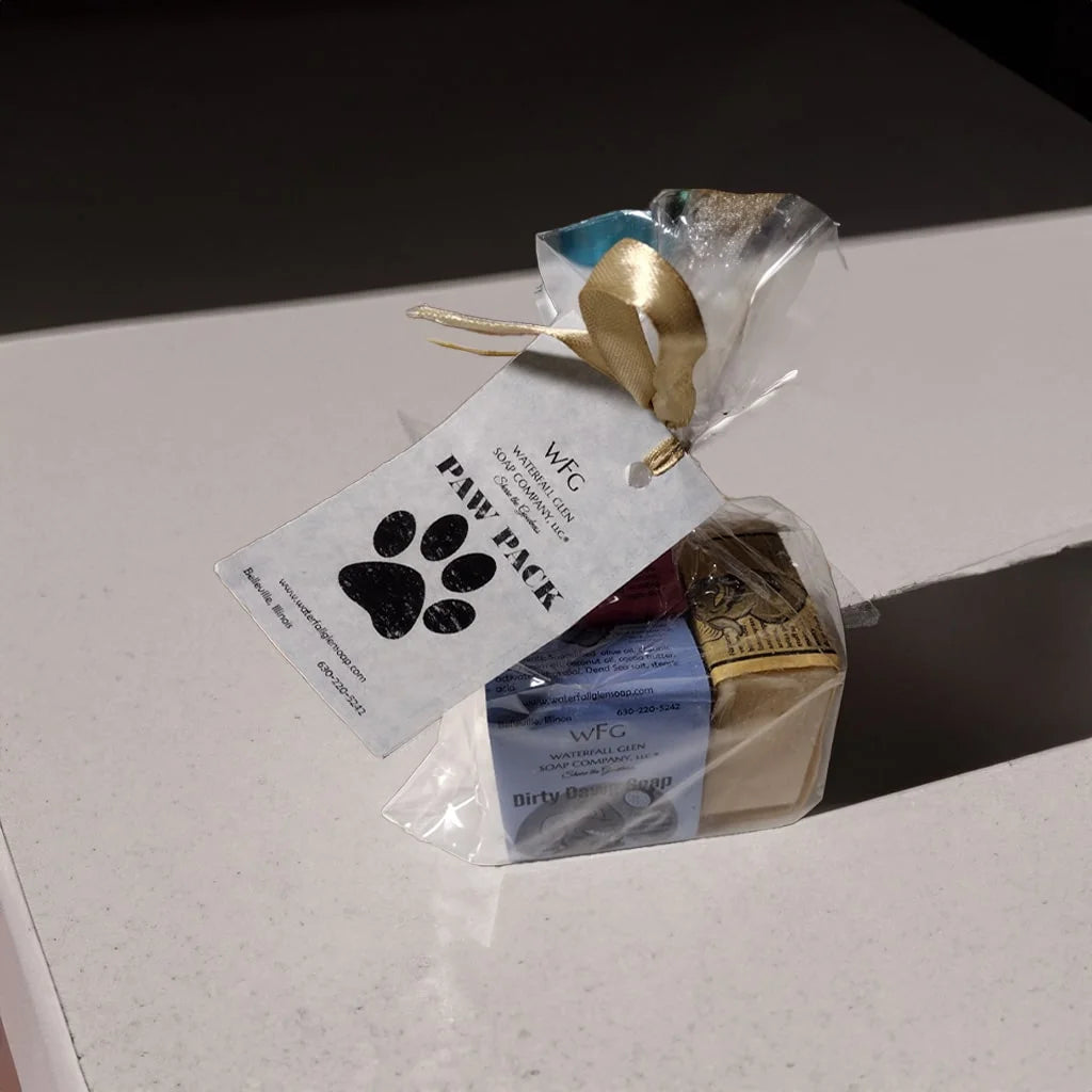 A 3 pack of the dirty dawg bar soap series in a plastic wrapping with a Paw Pack label that has a dog print on it. Sitting on top of a table countertop.