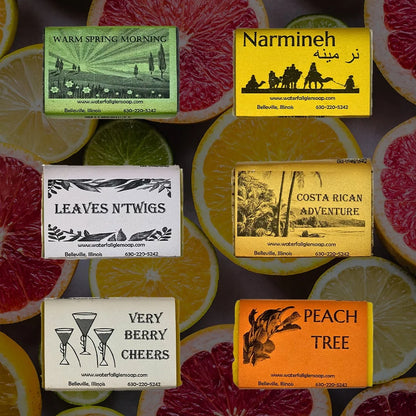 Six citrus scented bar soaps in front of a background consisting of oranges, lemons, limes, and grapefruits